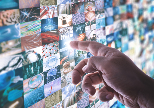 The hand touches the touchscreen led panel with various images about technology and science.