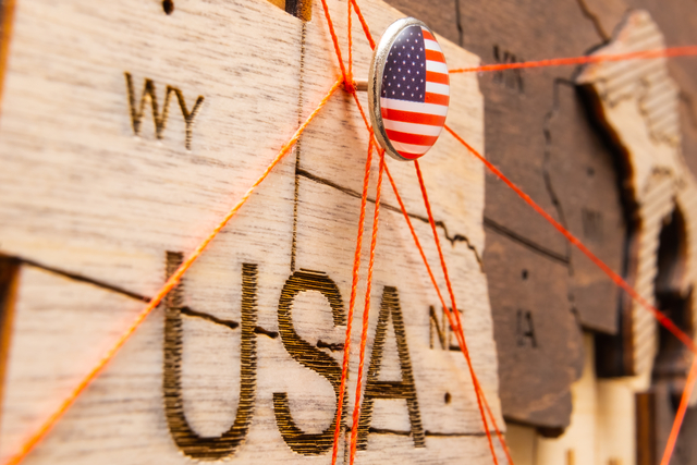 USA flag pins and red thread for traveling and planning trips. Planning of logistics routes or spheres of influence in geopolitics